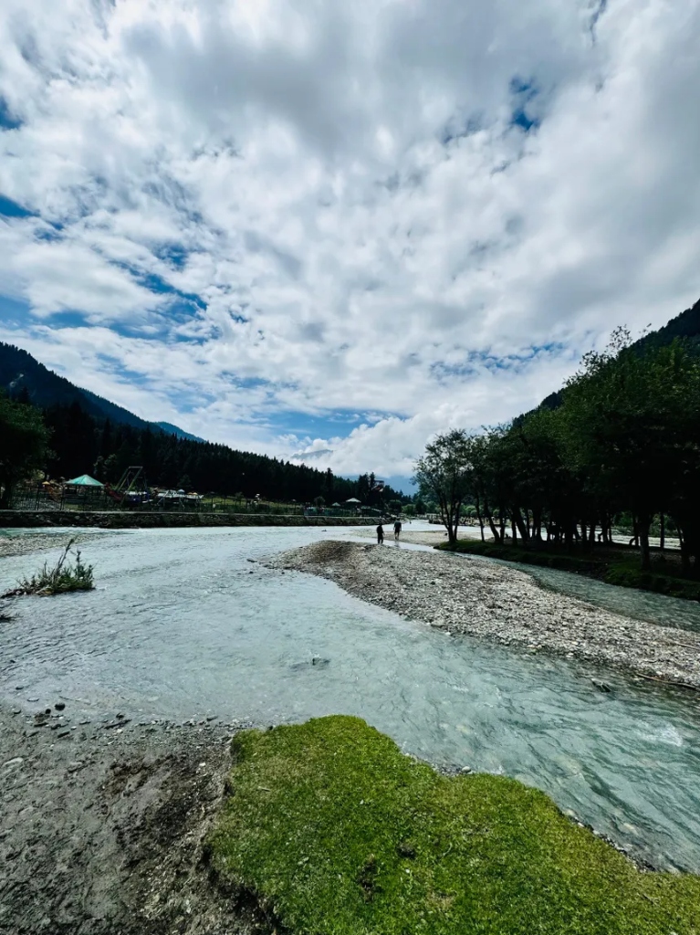 Lidder river rushing over pebbles under dramatic clouds