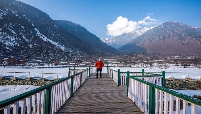 Winter wooden bridge view of snow-covered Pahalgam terraces