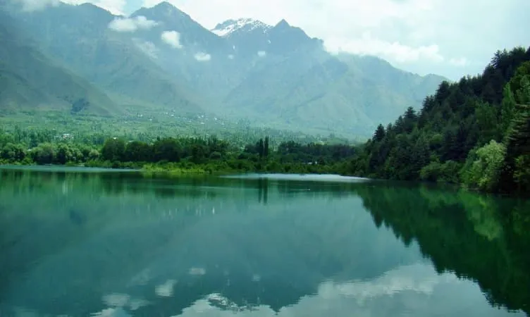 Emerald alpine mountain lake reflecting steep Himalayan peaks