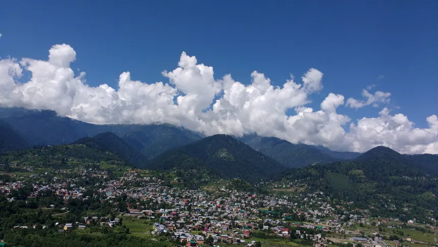 Bhaderwah town in green valley basin under blue skies and clouds