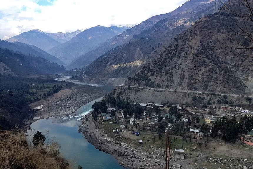 Chenab valley highway winding through mountains with distant snow peaks